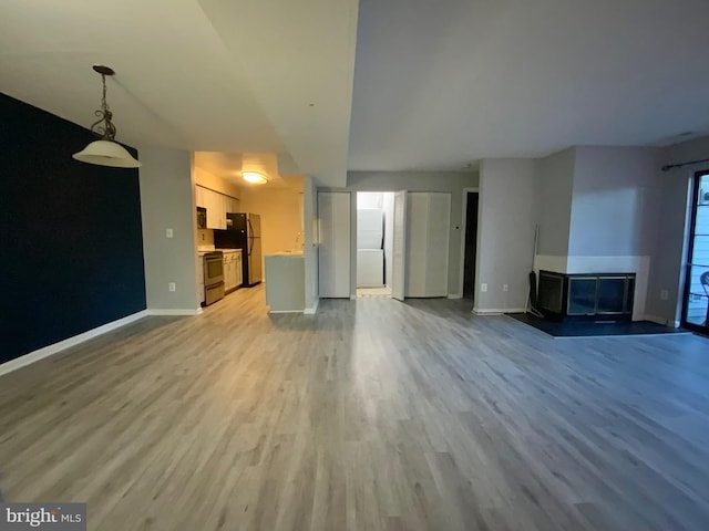 unfurnished living room featuring light hardwood / wood-style flooring and a multi sided fireplace