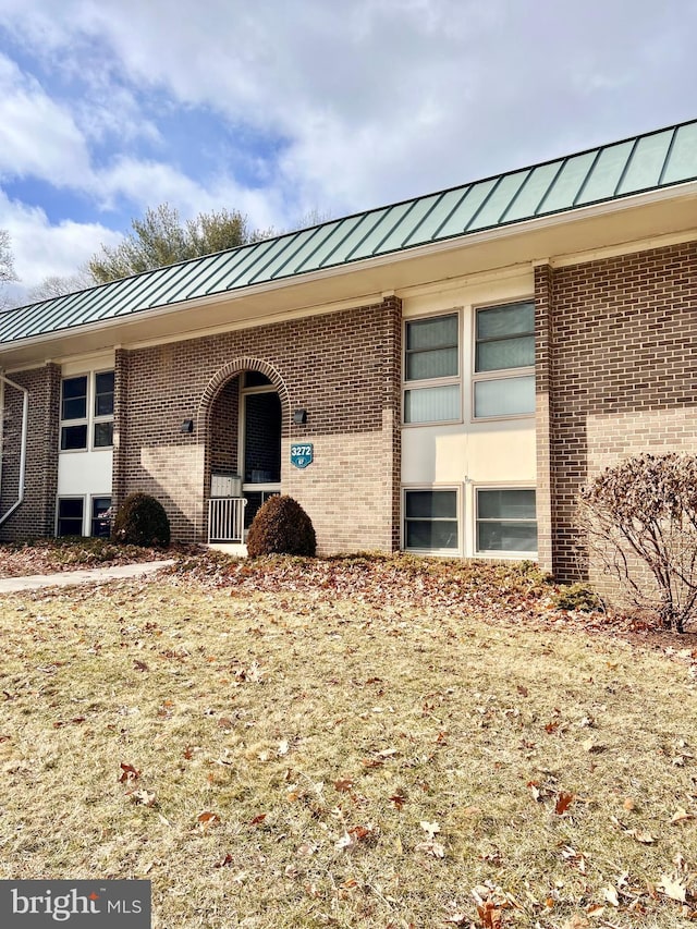 entrance to property with a standing seam roof, metal roof, and brick siding