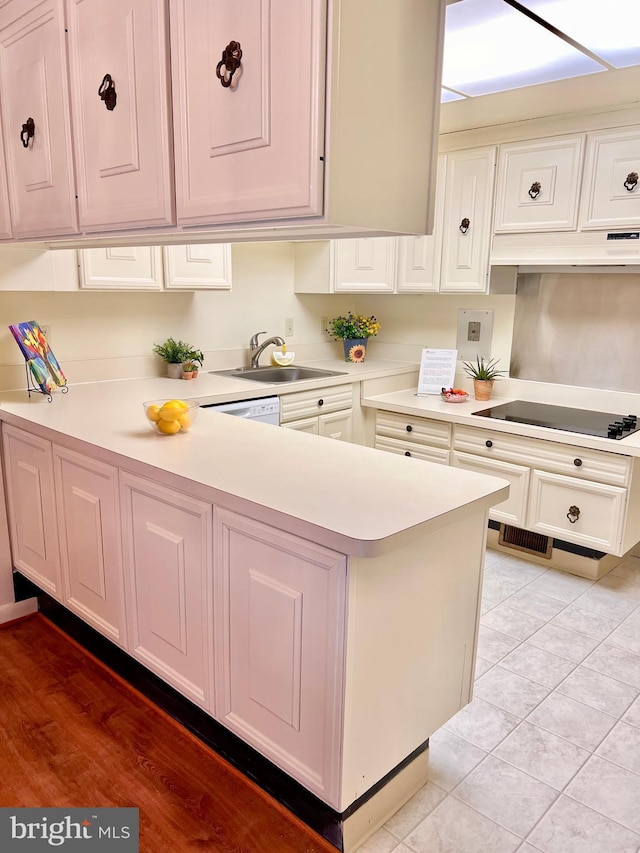 kitchen with light countertops, a sink, black electric cooktop, and white cabinetry