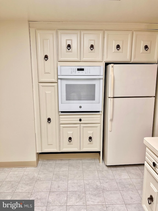 kitchen with light countertops, white appliances, light tile patterned flooring, and cream cabinets