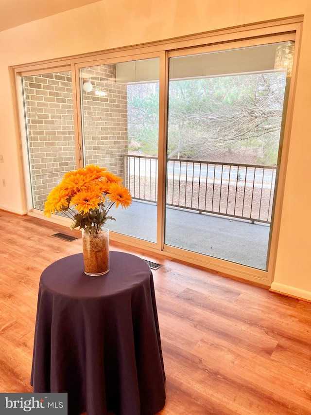 doorway to outside featuring wood finished floors, visible vents, and baseboards