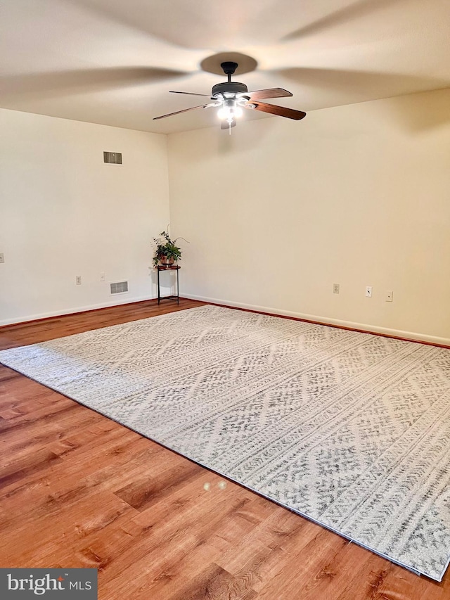 unfurnished room featuring baseboards, wood finished floors, visible vents, and a ceiling fan