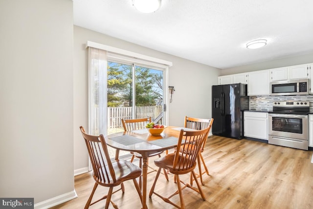 dining area featuring baseboards and light wood finished floors