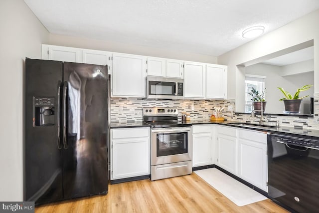 kitchen featuring black appliances, dark countertops, and white cabinetry