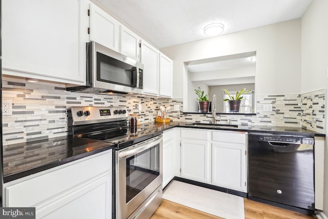 kitchen featuring dark countertops, white cabinetry, and appliances with stainless steel finishes