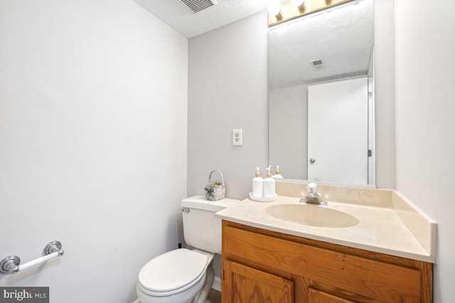 bathroom with toilet, visible vents, a textured ceiling, and vanity