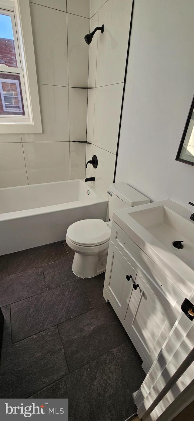 full bathroom featuring vanity, tiled shower / bath combo, and toilet