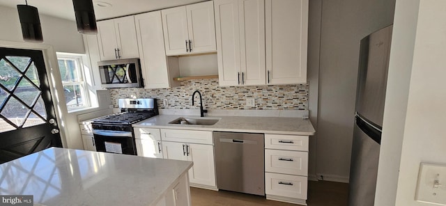 kitchen with appliances with stainless steel finishes, decorative light fixtures, sink, white cabinets, and decorative backsplash