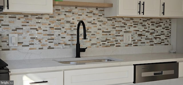 kitchen featuring white cabinetry, sink, tasteful backsplash, and light stone countertops