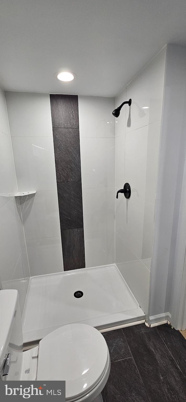 bathroom featuring tiled shower and toilet