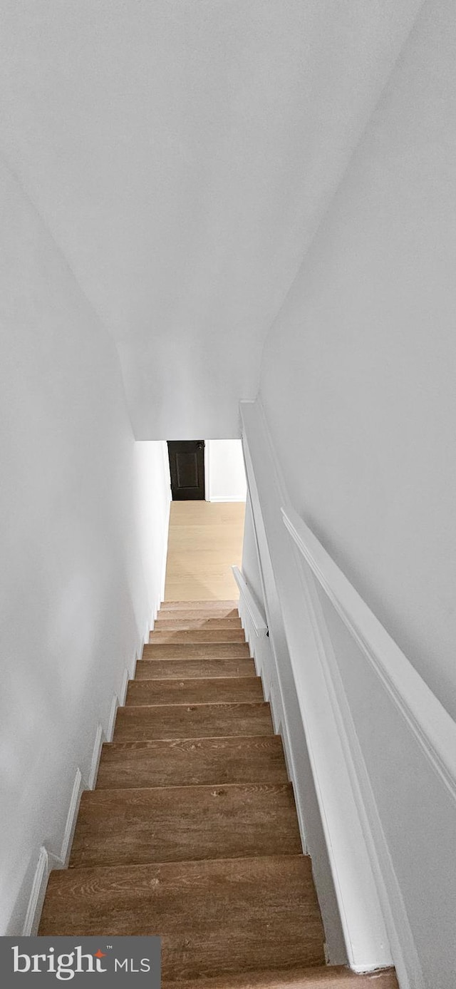 stairs featuring lofted ceiling and wood-type flooring