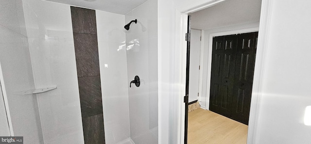 bathroom with hardwood / wood-style flooring and tiled shower