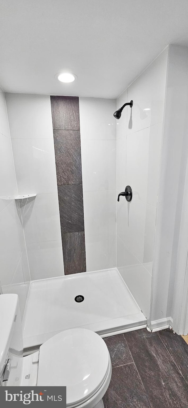 bathroom with tiled shower and toilet