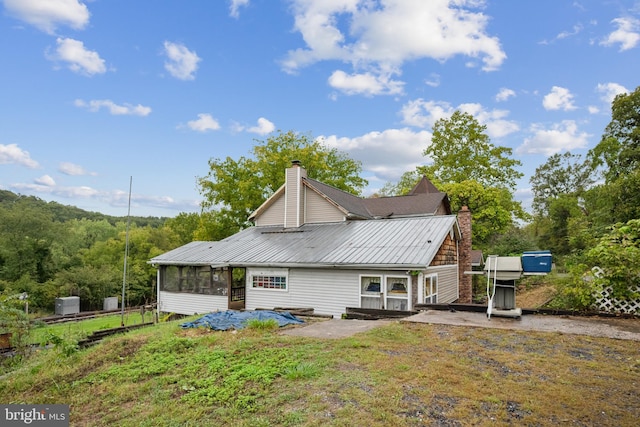 rear view of house featuring a patio area, a sunroom, and a lawn