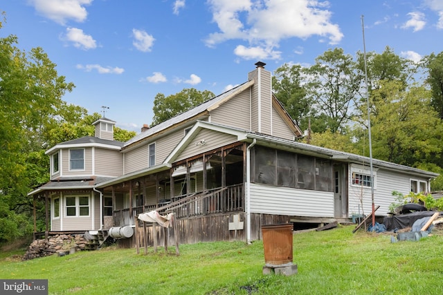 rear view of house with a sunroom and a lawn