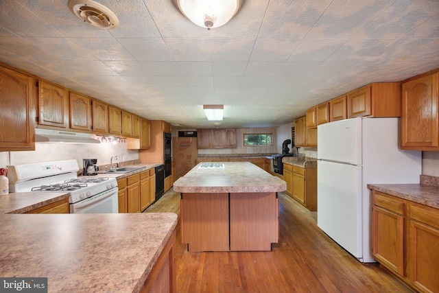 kitchen featuring sink, wood-type flooring, black appliances, and a kitchen island