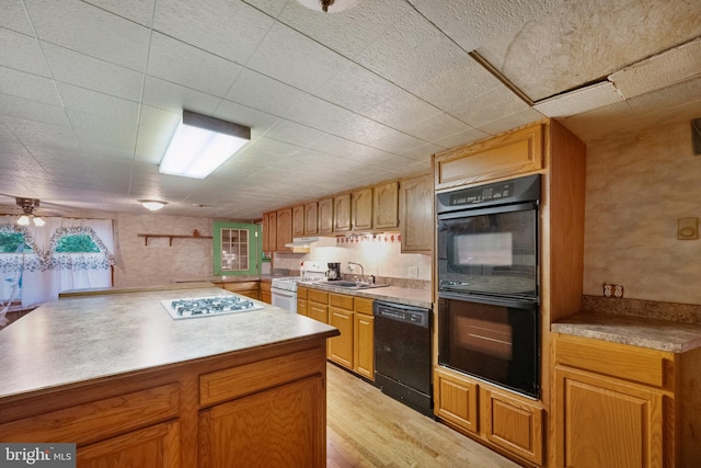 kitchen featuring black appliances, sink, ceiling fan, kitchen peninsula, and light wood-type flooring