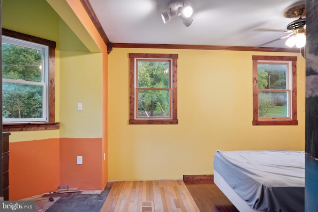 bedroom with ornamental molding, wood-type flooring, and ceiling fan