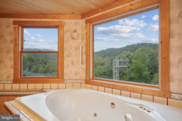 bathroom with wood ceiling, a wealth of natural light, and a bathing tub