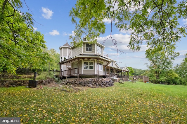 rear view of house featuring a wooden deck and a lawn