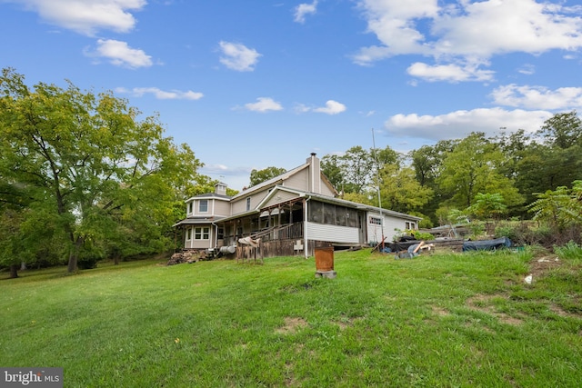 rear view of house with a sunroom and a yard