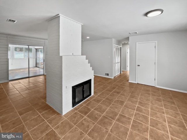 unfurnished living room featuring a brick fireplace and tile patterned floors