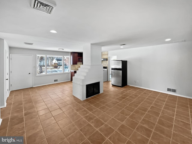 unfurnished living room with tile patterned floors and washer / clothes dryer