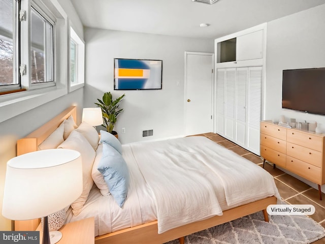 bedroom with dark tile patterned floors and a closet