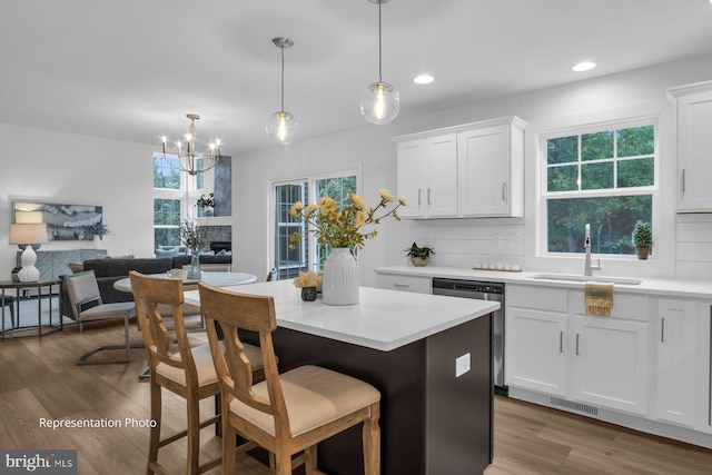 kitchen with pendant lighting, sink, dishwasher, and white cabinets