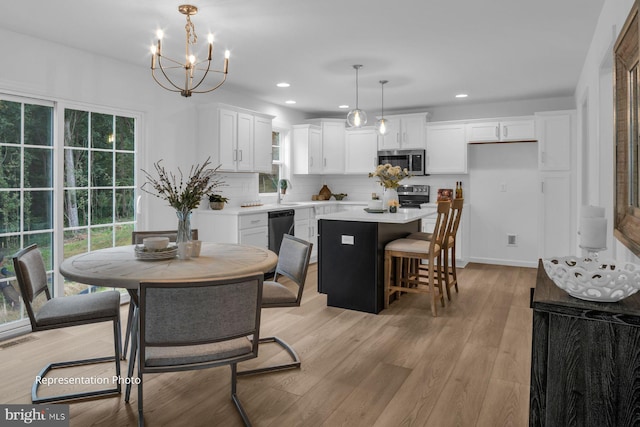 dining area with a healthy amount of sunlight, a chandelier, and light hardwood / wood-style flooring