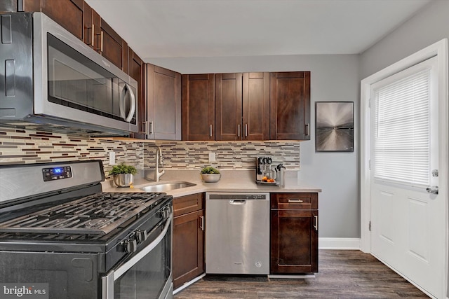 kitchen with sink, appliances with stainless steel finishes, backsplash, dark brown cabinets, and dark hardwood / wood-style flooring