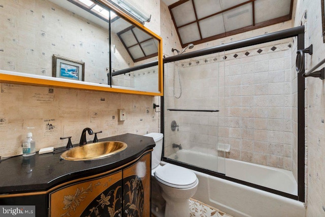 full bathroom featuring toilet, vanity, and shower / bath combination with glass door