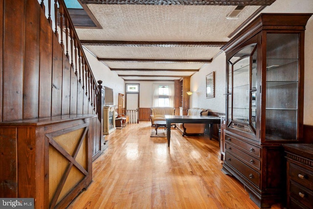 interior space featuring a textured ceiling, light hardwood / wood-style flooring, and beamed ceiling