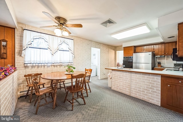 kitchen featuring sink, ceiling fan, carpet, black appliances, and brick wall