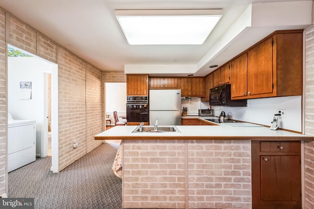 kitchen with brick wall, washer / dryer, sink, stainless steel fridge, and kitchen peninsula