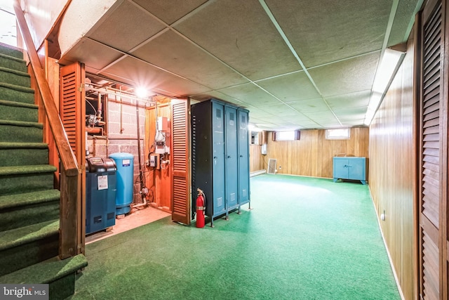 basement featuring a paneled ceiling and wooden walls