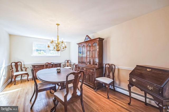 dining area featuring a chandelier, light wood-type flooring, and baseboard heating