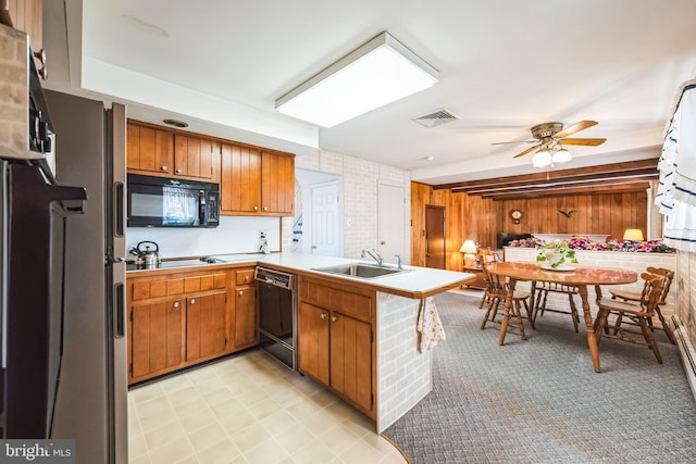 kitchen with kitchen peninsula, wooden walls, sink, ceiling fan, and black appliances