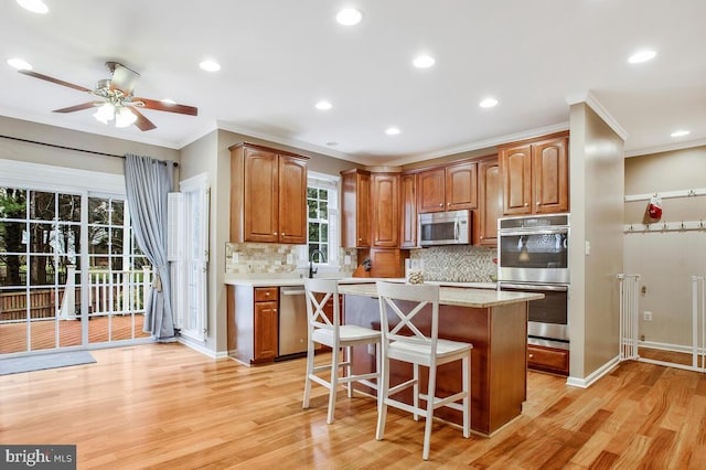 kitchen with sink, light hardwood / wood-style flooring, a breakfast bar, appliances with stainless steel finishes, and a kitchen island