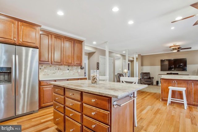 kitchen featuring decorative backsplash, a center island, ceiling fan, stainless steel fridge with ice dispenser, and light wood-type flooring