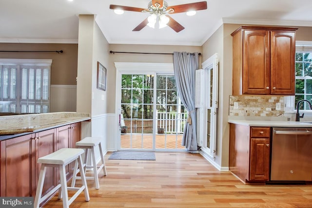 kitchen with tasteful backsplash, sink, ornamental molding, stainless steel dishwasher, and light hardwood / wood-style floors