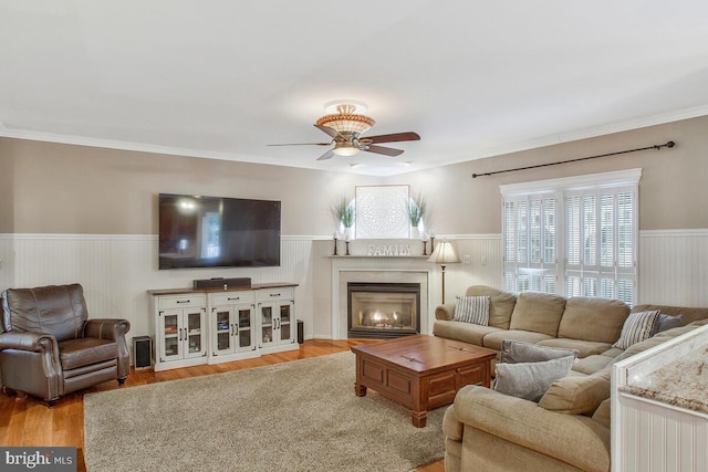 living room with ceiling fan, crown molding, and light wood-type flooring