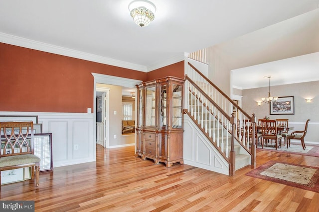 stairway with hardwood / wood-style flooring, ornamental molding, and a chandelier