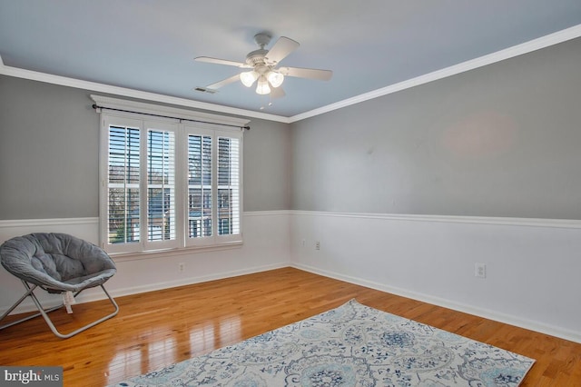 living area featuring wood-type flooring, ceiling fan, and crown molding