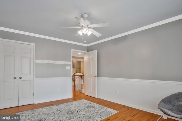 living area featuring crown molding, wood-type flooring, and ceiling fan