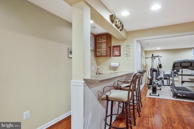 kitchen featuring hardwood / wood-style flooring, a breakfast bar, and kitchen peninsula