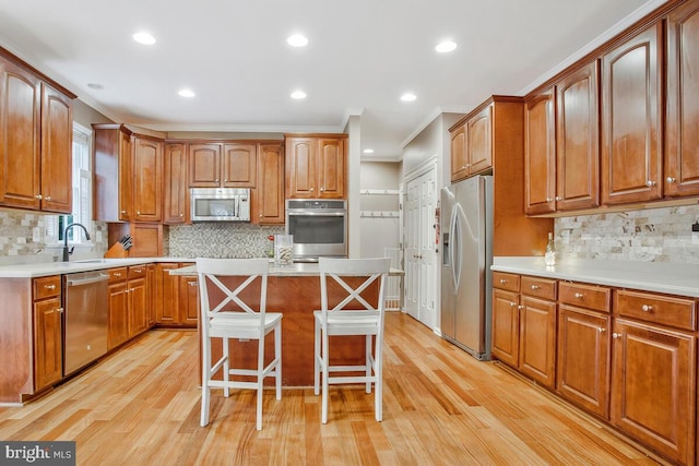 kitchen with stainless steel appliances, a kitchen bar, a kitchen island, and light wood-type flooring