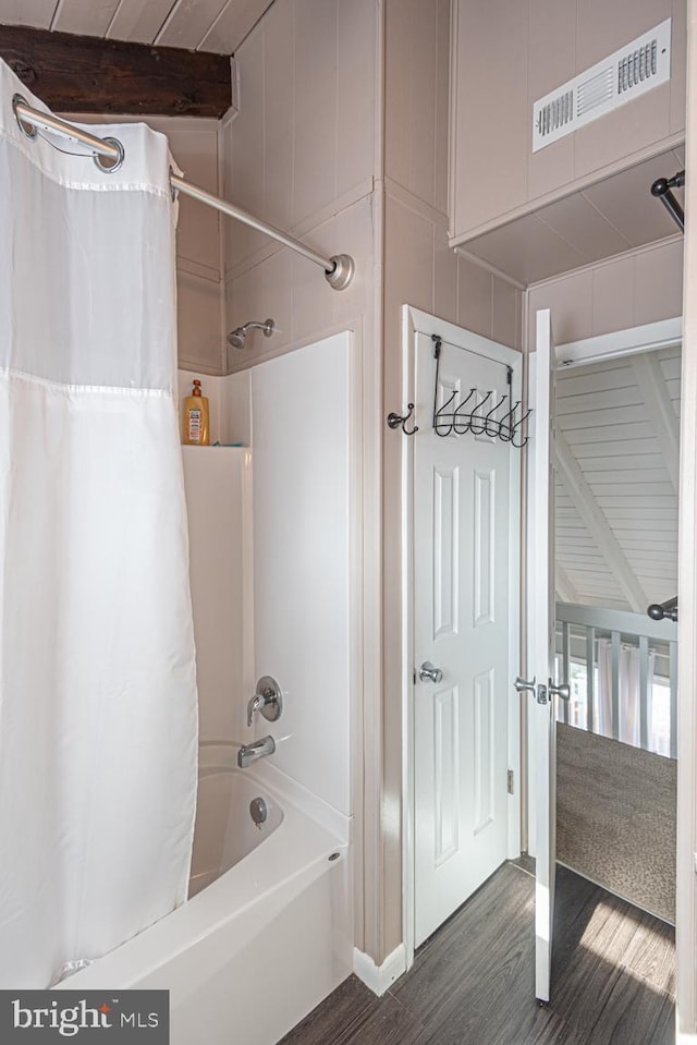 bathroom featuring wood-type flooring, shower / tub combo, and beam ceiling