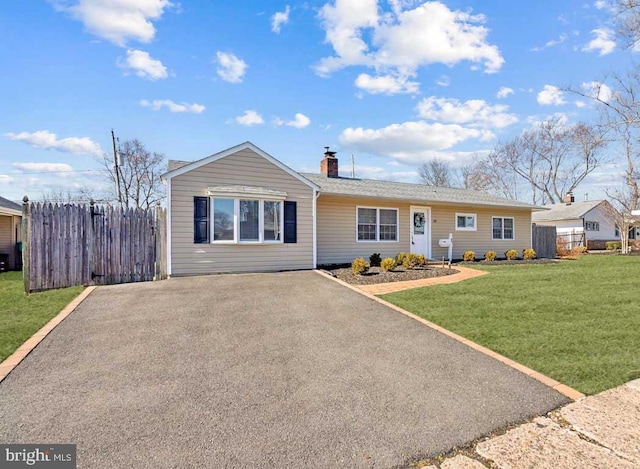 single story home featuring a front lawn, fence, driveway, and a chimney