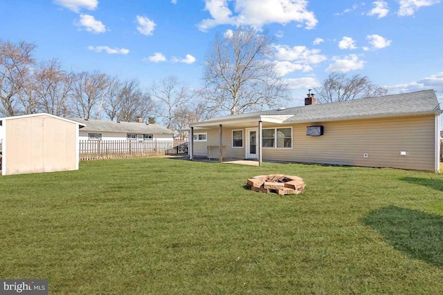 rear view of house with an outdoor structure, a yard, a fire pit, and fence